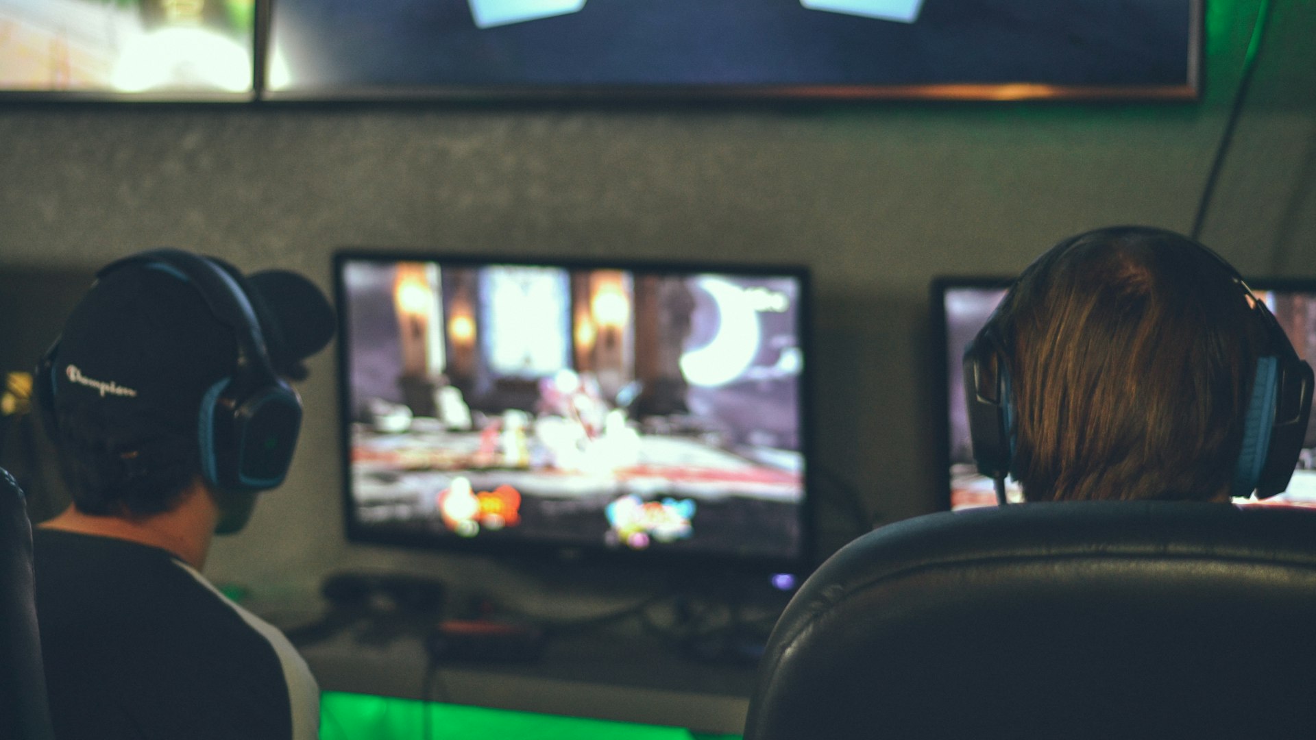 A cosy neon-lit gaming desk setup surrounded by plants